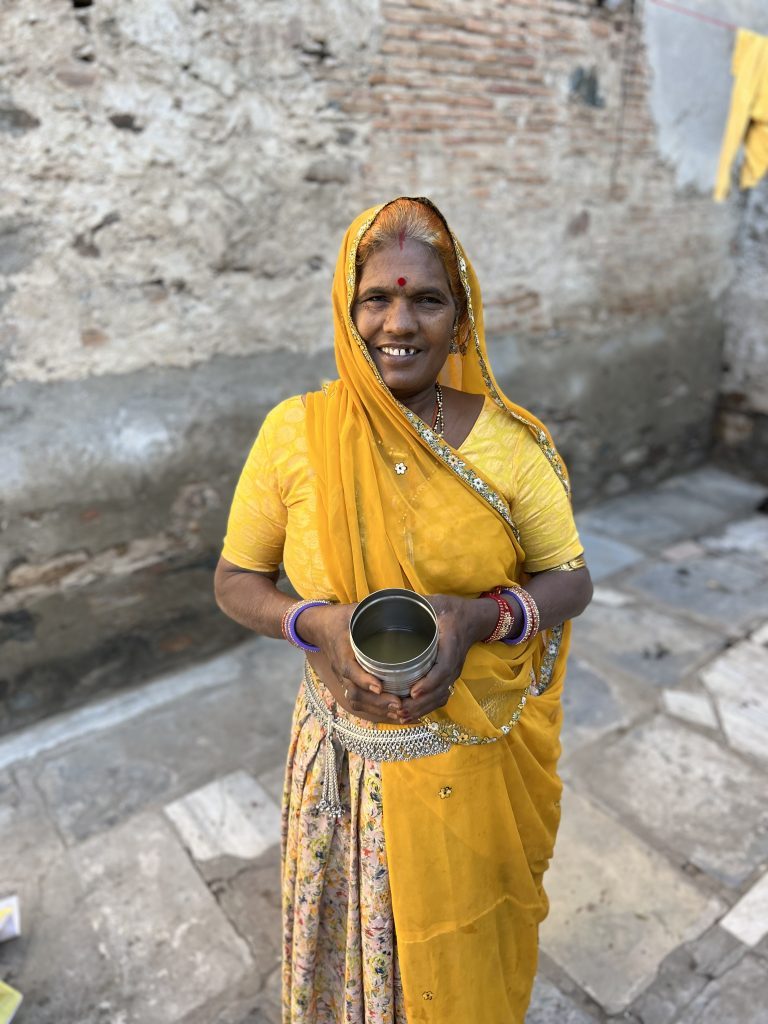 Kanku Bai in a yellow sari, holding a tin of lemongrass oil